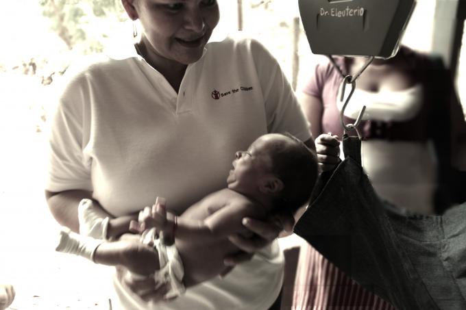 Una técnico de Save the Children pesando a un bebé recién nacido. San Pedro
