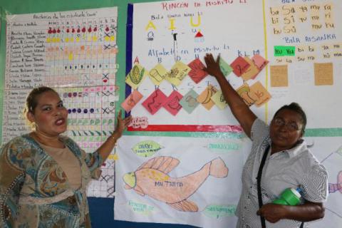 Elba Tilleth Ramsiu  junto a Kenia Vanessa Hernández Richardson mostrando trabajos de la clase de lengua miskita.
